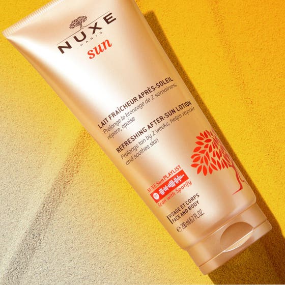 Nuxe Sun Refreshing After Sun Lotion 200 ml fuktighetskrem i bronsefarget tube på gyllen sand