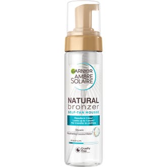 Garnier Ambre Solaire Natural Bronzer Self-Tan Mousse gir glød i en klar plastflaske med gullfarget pumpe og lokk