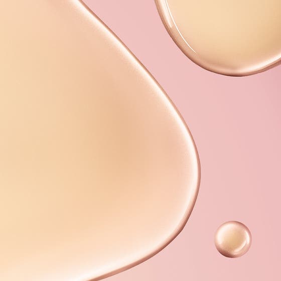 Nuxe Huile Prodigieuse Florale 100 ml kroppsolje i rosa glassflaske holdes mot huden og gir en fuktig, strålende glød