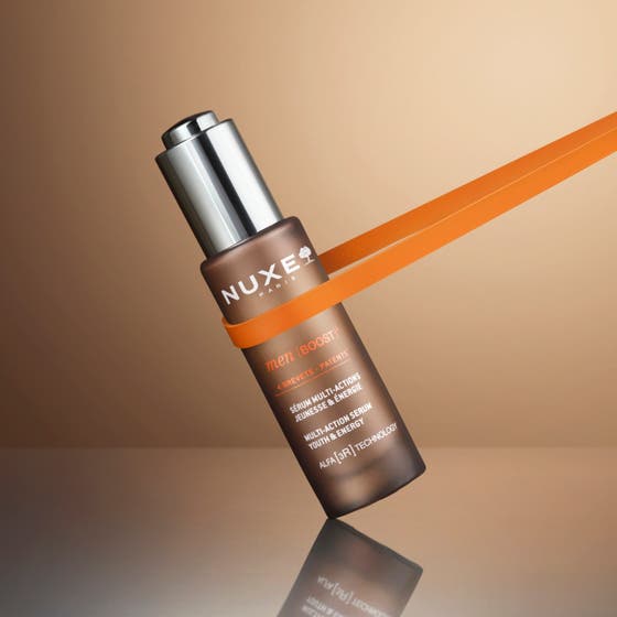 Nuxe Men Multi Action Serum 30 ml gir fuktighet vist på en smilende mann med hendene på ansiktet.