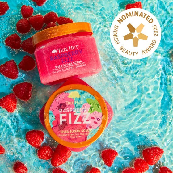 Tree Hut Shea Sugar Scrub Raspberry Fizz 510 g kuorinta-aine vadelmien ja veden ympäröimänä.