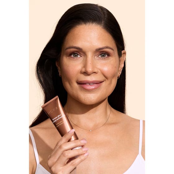Hickap Bronze Glow Priming Moisturizer bronskräm ger lyster och visas av en kvinna med en bronsfärgad tub.