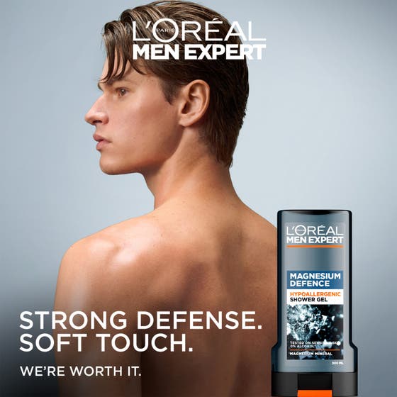 L'Oréal Paris Men Expert Magnesium Defence 300 ml dusjsåpe som beroliger sensitiv hud holdes i en hånd utendørs.