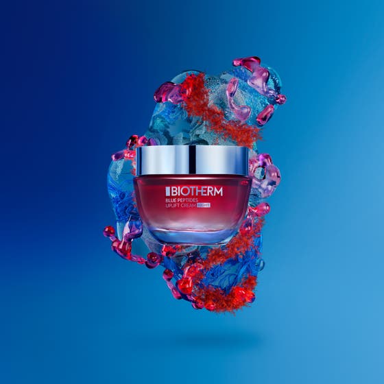 Biotherm Blue Peptides Uplift 50 ml nattkrem i rød glasskrukke med sølvlokk mot en blå abstrakt bakgrunn.