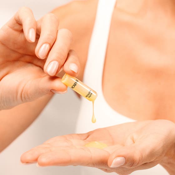 Babor Nutri Restore Ampoule 14 ml næringsgivende serum for ansiktsvård i en glassampulle som holdes av hender.