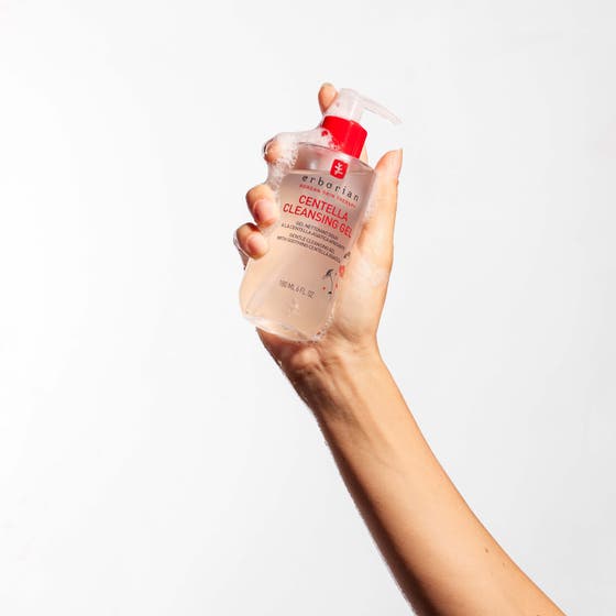 Erborian Centella Cleansing Gel 180 ml fuktighetsgivende ansiktsrens i pumpeflaske holdt i en hånd med skum.