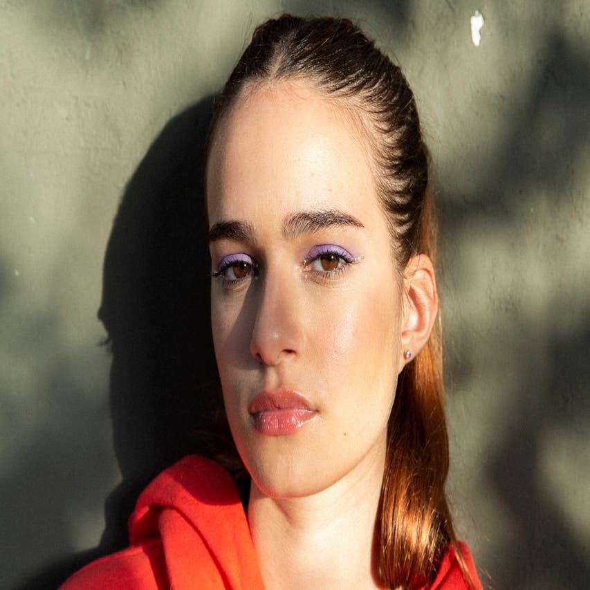 Närbild på en kvinna med lila ögonskugga och röd hoodie.