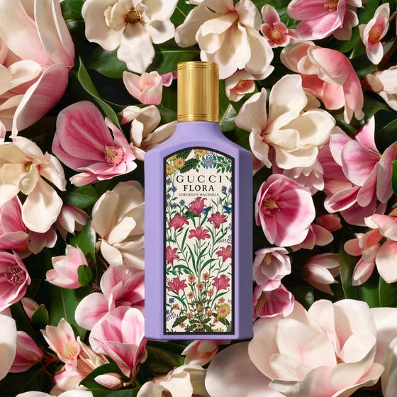 Gucci Flora Gorgeous Magnolia 50ml damparfym i lila flaska med guldkork placerad bland vita och rosa magnolior